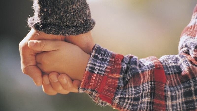 Ein Kind hält die Hand einer erwachsenen Person