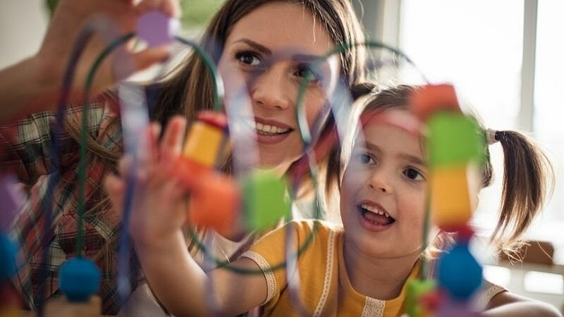 Eine Frau und ein Kind spielen gemeinsam mit buntem Spielzeug.