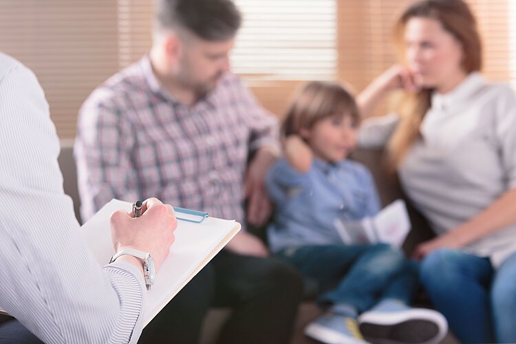 Eltern und Kind sitzen gemeinsam in einem Beratungsgespräch.