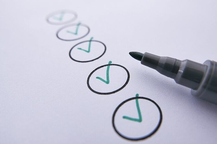 Stift neben einer Checkliste mit markierten Häkchen.