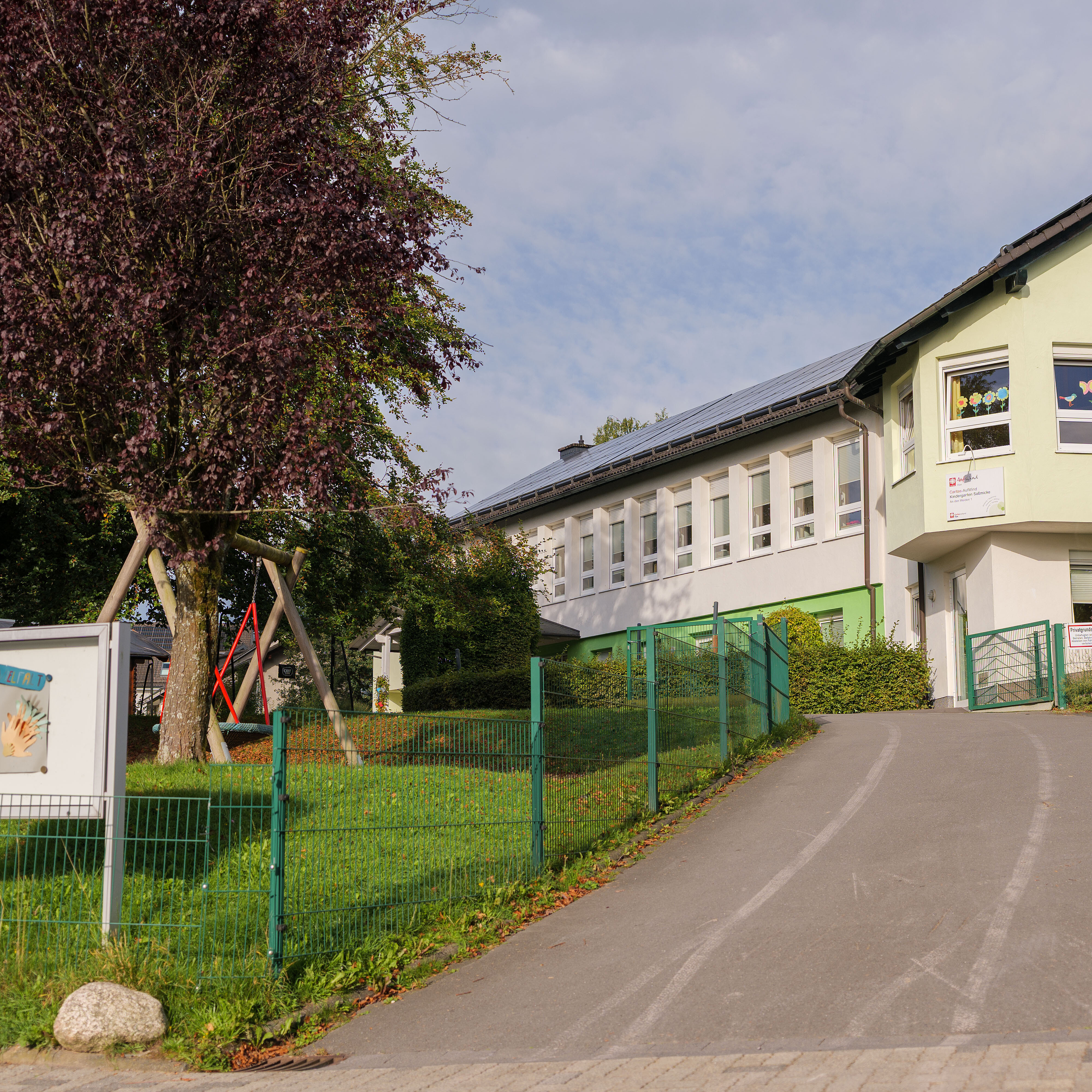 Außenansicht der Caritas-AufWind Kita Saßmicke mit Zufahrtsweg, Eingangsbereich und Grünfläche