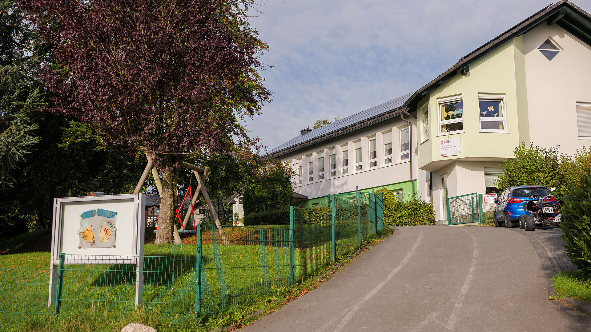 Außenansicht der Caritas-AufWind Kita Saßmicke mit Zufahrtsweg, Eingangsbereich und Grünfläche