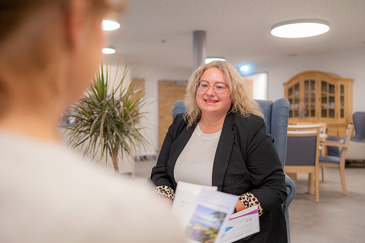 Eine Frau spricht mit einer anderen Person in einem Beratungsraum.