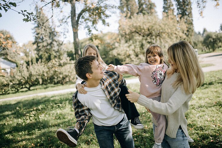 Eine Familie mit zwei kleinen Kindern, von denen eines auf dem Rücken getragen wird.