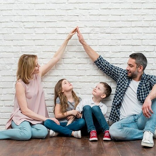 Mutter und Vater bilden mit ihren Armen ein schützendes Dach über ihrer Tochter.